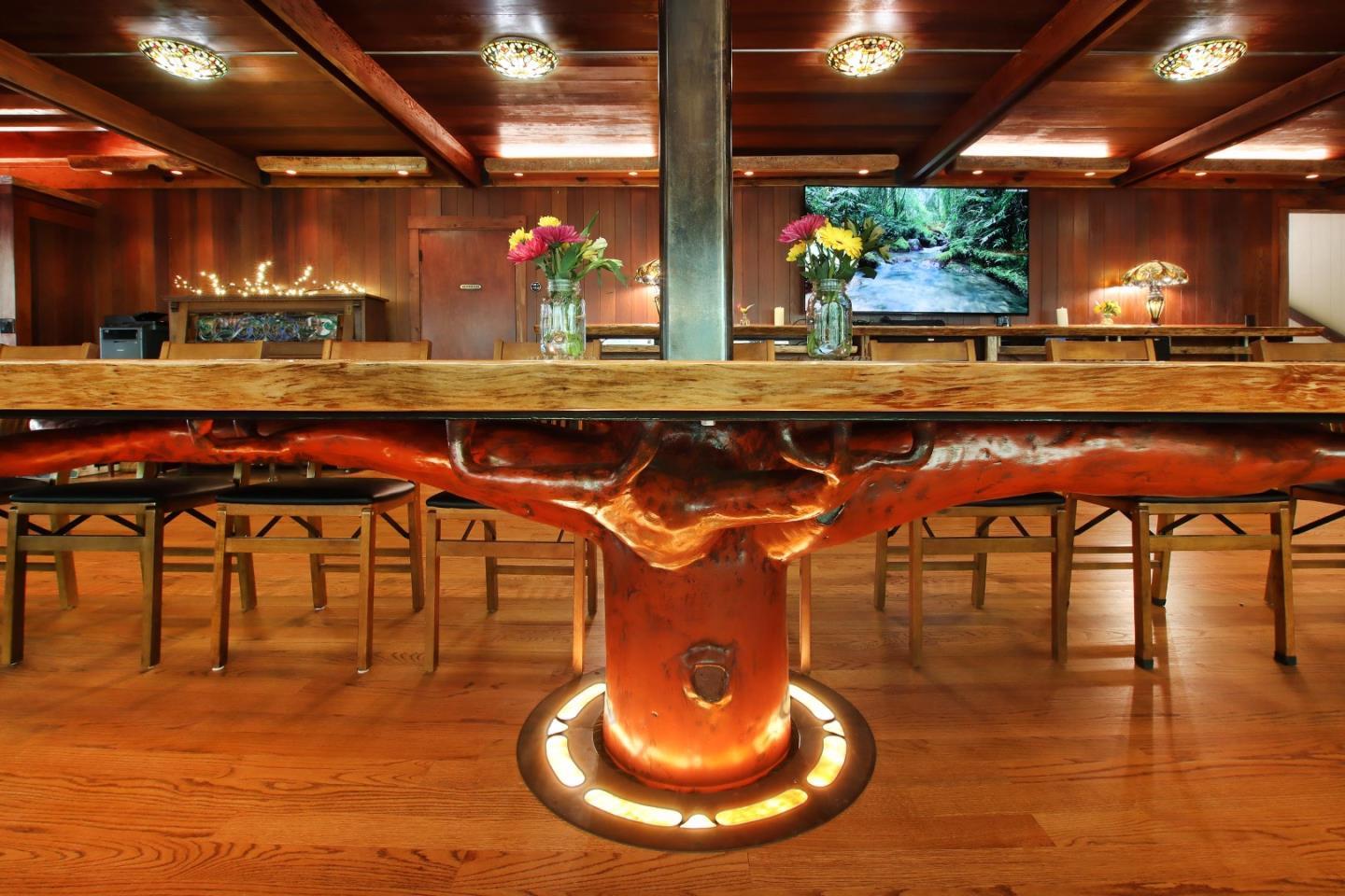 Wood-paneled dining room with a large live-edge table and sculptural wooden pedestal.