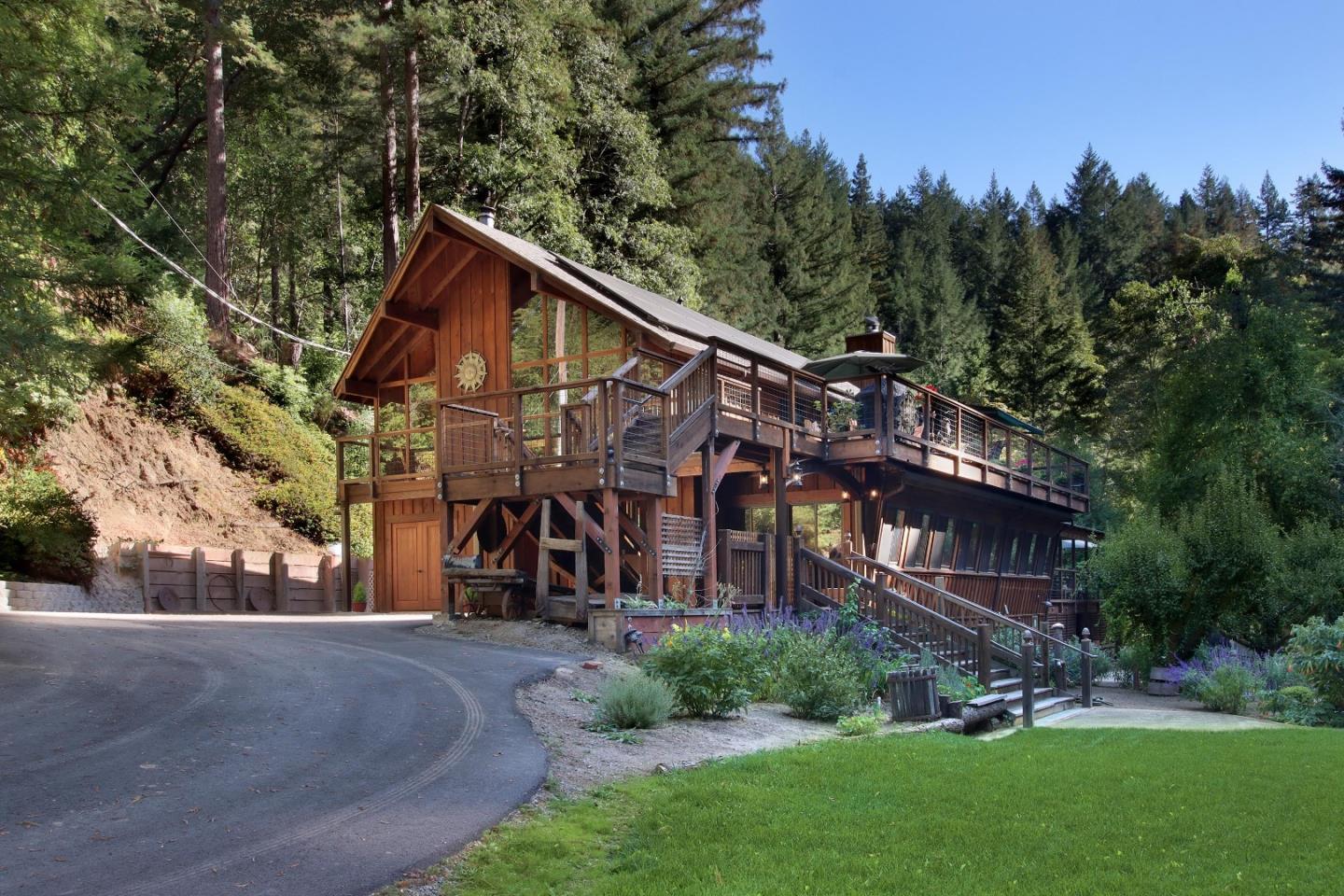 Wood lodge-style home with a long elevated deck and curved driveway, surrounded by trees.